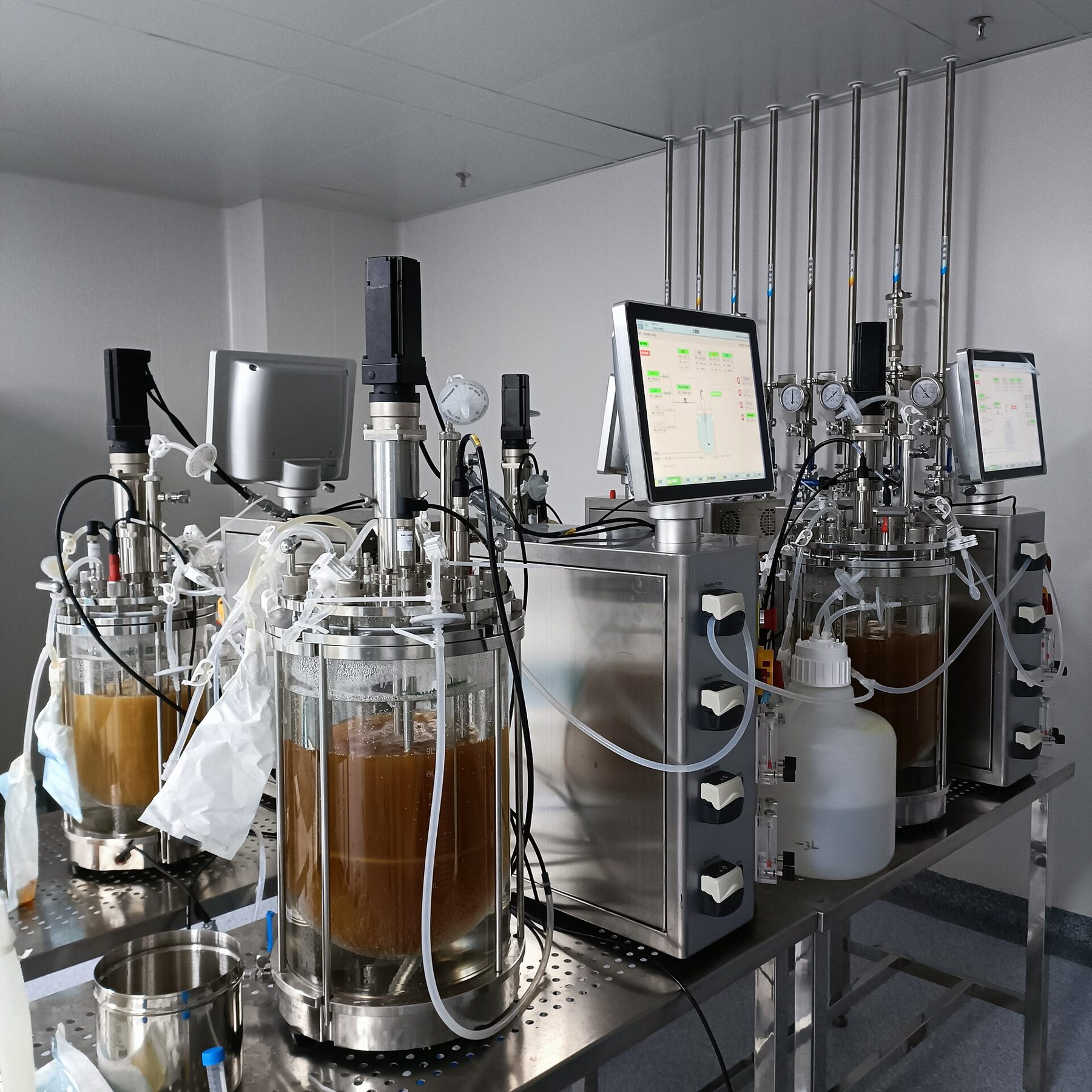 Glass bioreactors with culture medium and their control units on a laboratory bench
